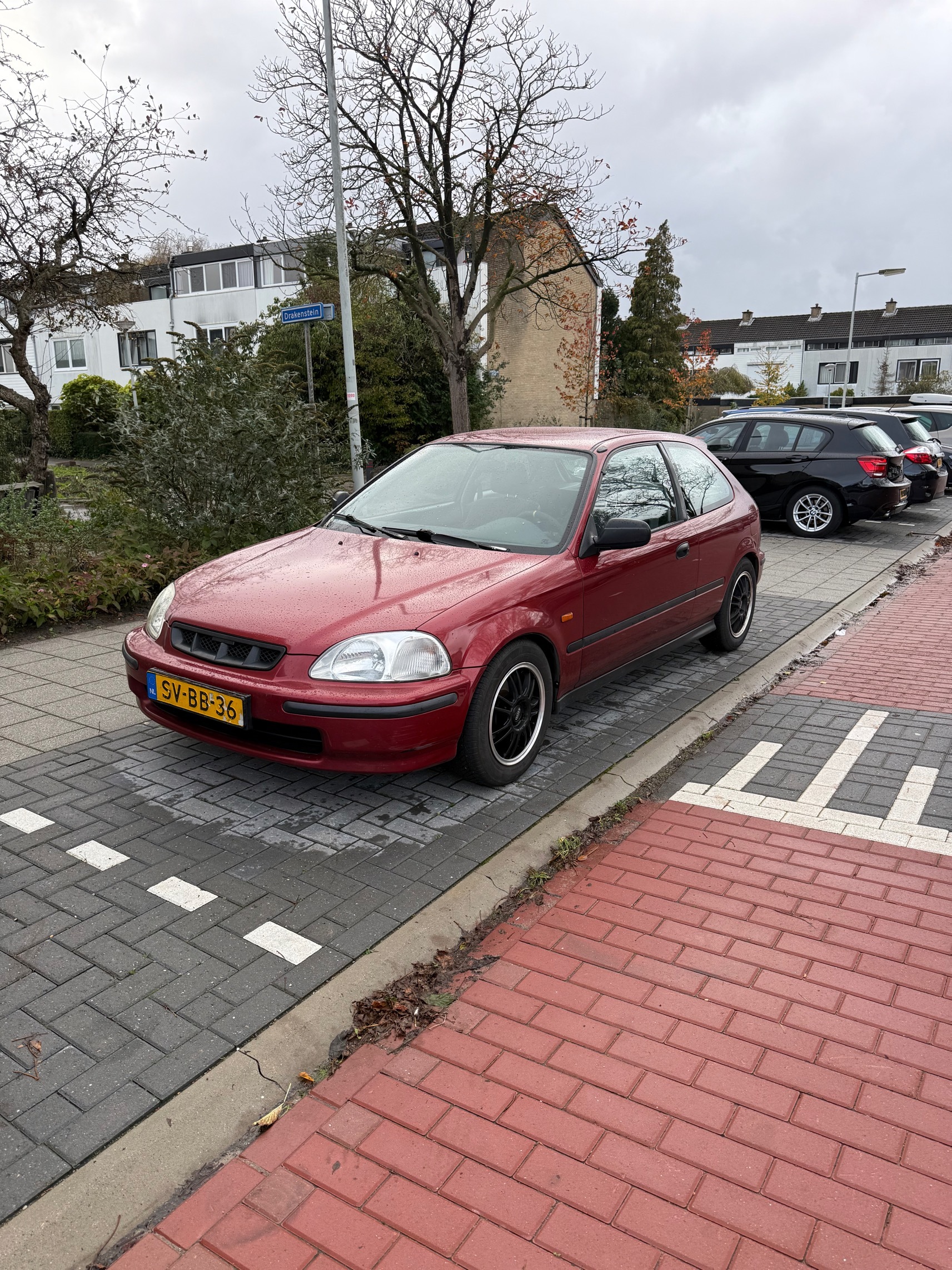Rode Honda Civic 3-deurs uit 1998, geparkeerd in een woonwijk